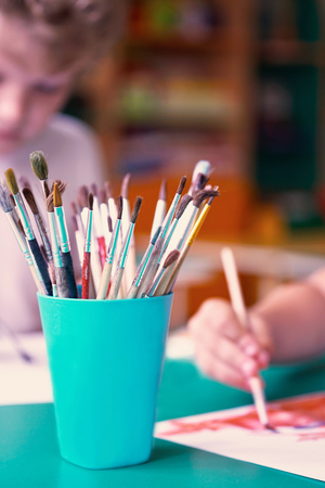 Box with brushes for drawing closeup.Little boys drawing paints on the background. School, education concept.の写真素材