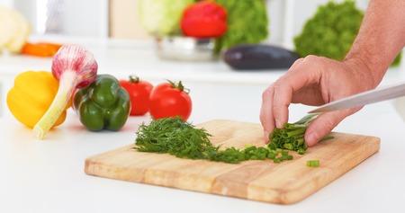Hands of man is cooking vegetable salad in the kitchen closeup.の写真素材