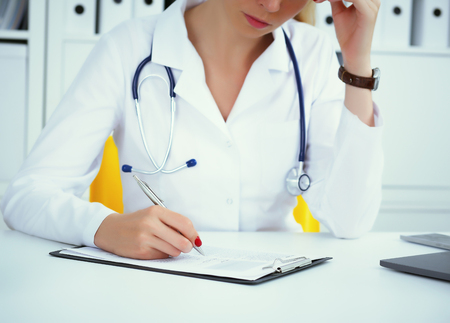 Close-up view of female doctor hands filling patient registration form. Healthcare and medical conceptの写真素材