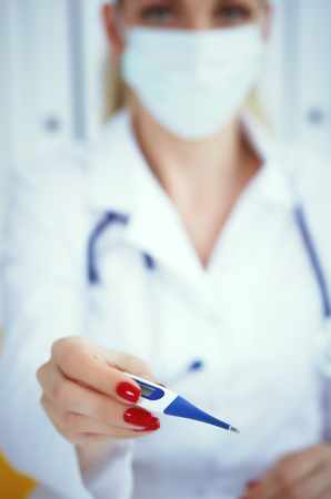 Female doctors hands giving clinical thermometer. Healthcare personnel, medicine conceptの写真素材