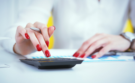 Close up hand of female accountant or banker making calculations. Savings, finances and economy conceptの写真素材