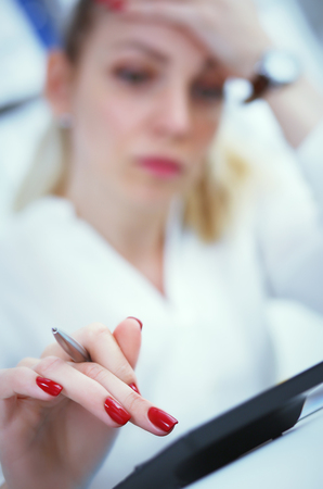 Tired business woman or female accountant calculate the losses on a calculator in office. Photo with depth of field.の写真素材