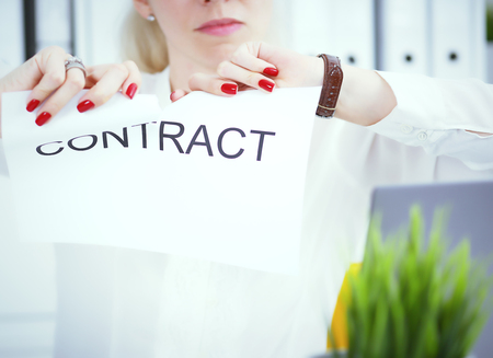 Angry woman tears agreement documents in front of camera closeup.の写真素材