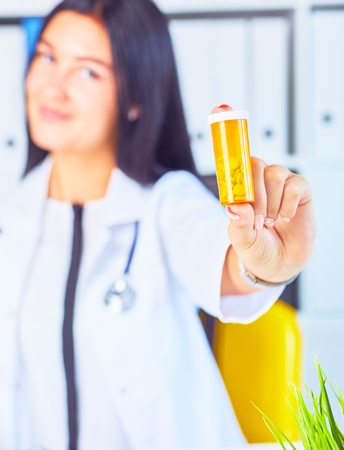 Woman doctor offers a jar of pills to the patientPanacea and life save, prescribe antidepressant, legal drug store, ward round, give or take potion, vitamin aid conceptの写真素材