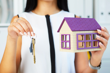 Young businesswoman or real estate agent with hose model and keys in hands closeup.の写真素材