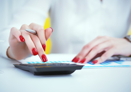 Close up hand of female accountant or banker making calculations. Savings, finances and economy conceptの写真素材