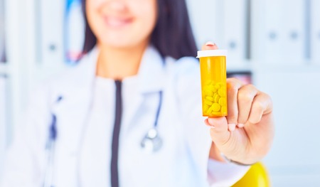 Woman doctor offers a jar of pills to the patientPanacea and life save, prescribe antidepressant, legal drug store, ward round, give or take potion, vitamin aid conceptの写真素材