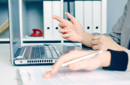 Hands of two business women sitting together and working on laptop. Executives meeting in a office lobby. Woman pointing at laptop.の写真素材