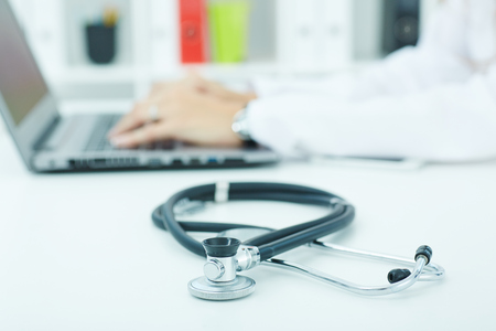 Medical stethoscope lying on the desk closeup while medicine doctor working in background. Health, protection, prevention and help. Healthy life or insurance conceptの写真素材