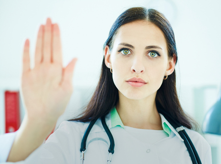 Beautiful female medical doctor showing stop gesture. Health, protection, prevention and help. Healthy life or insurance concept.の写真素材