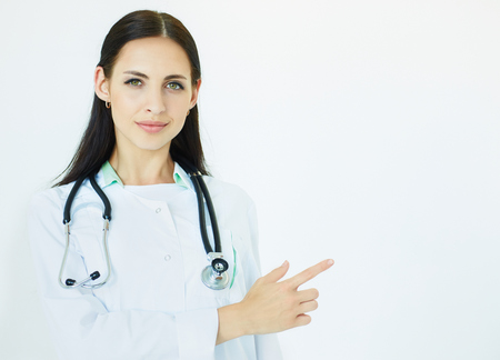 Young beautiful female doctor with stethoscope pointing to the copy space for product or text. Advertisement concept.の写真素材