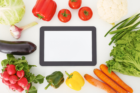 Blank screen tablet lying surrounded by vegetables. Cooking dinner, searching recipe on the Internet.の写真素材