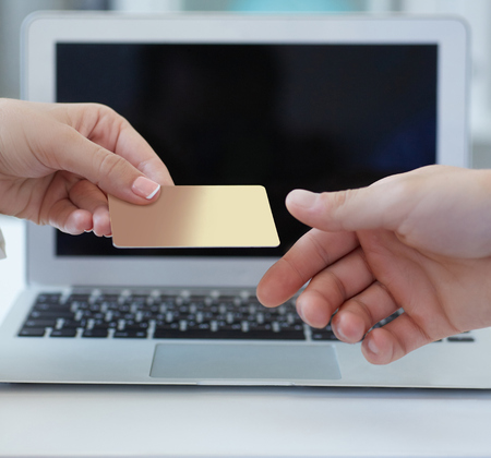 Closeup shot of a womans hand giving a payment credit card to the seller in computer store. Girl holding a credit card.の写真素材