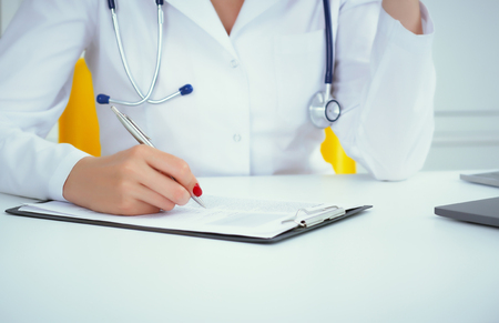 Close-up view of female doctor hands filling patient registration form. Healthcare and medical conceptの写真素材
