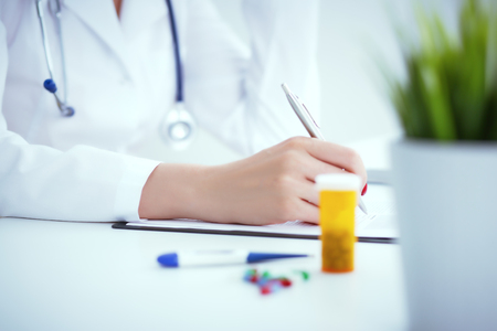 Close up of woman doctor taking notes. Photo with dept of field.の写真素材