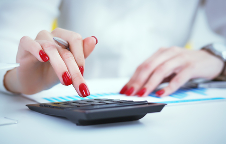 Close up hand of female accountant or banker making calculations. Savings, finances and economy conceptの写真素材