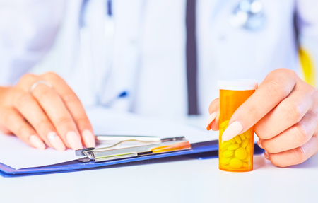 Female doctor hand hold a pill bottle and offer it to visitor. Panacea or life save antidepressant from legal store prescribe vitamin medic aid for healthy lifestyleの写真素材