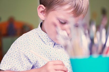 Concept of primary school education. The face of the drawing boy through a multitude of paint brushes.の写真素材