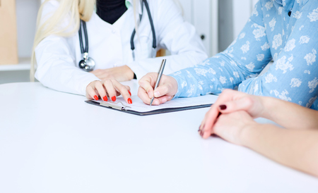 Doctor helps to fill the medical form. Just hands at the table.の写真素材