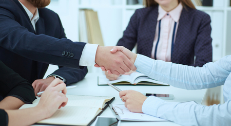 Male and female handshake in office close-up. Serious business and partnership concept. Partners made deal, sealed with handclasp.の写真素材