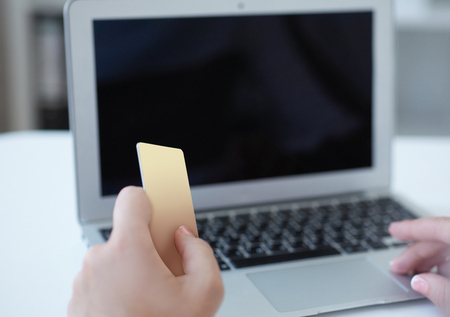 Closeup hand of girl typing credit card details on laptop to complete payment process. Close up of female hand paying bills online with laptop and credit card. Internet banking.の写真素材