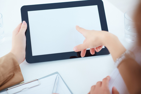Tablet blank screen for promotional messages. Two business women in a meeting discussing information on a tablet-pc.の写真素材