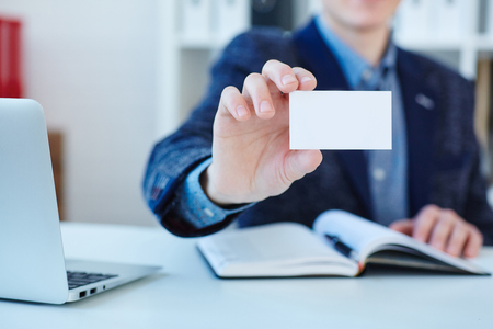 Businessman holding visit card close-up. Man showing blank business card. Person in blue suit. Mock up design.の写真素材