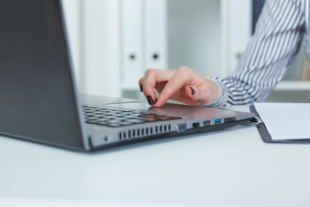 Close up of female hands typing on laptop keyboard in office background.の写真素材
