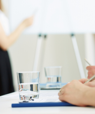 A glass of water in office workplace. The boardroom table is set for the Annual General Meeting. Water use for office workers. The concept of healthy eating in the workplace.の写真素材