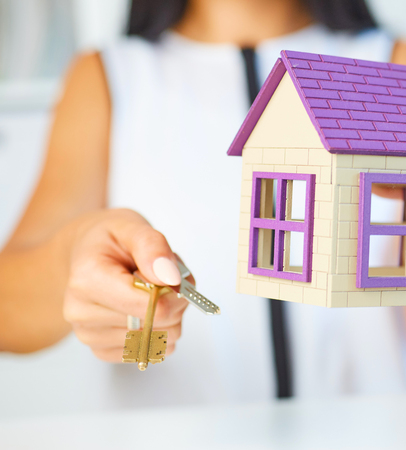 Young businesswoman or real estate agent with hose model and keys in hands closeup.の写真素材