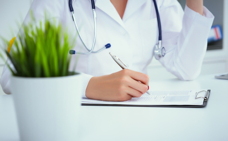 Close-up view of female doctor hands filling patient registration form. Healthcare and medical conceptの写真素材