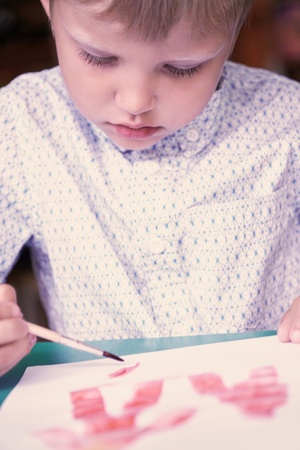 Little blonde Caucasian boy drawing with colorful watercolorsin the kindergarten. School, education concept.の写真素材
