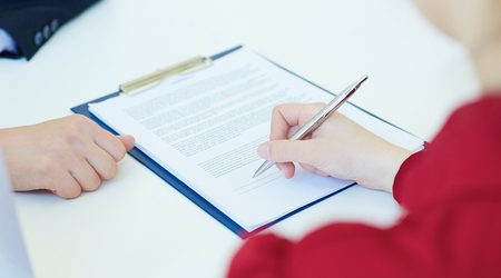 Hands of business woman signing the contract document with pen on desk. Photo with depth of field.の写真素材
