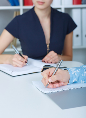Business man making notes at office workplace with his female colleague on the background. Business job offer, financial success, certified public accountant concept.の写真素材