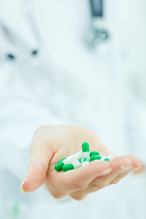 Young female doctor showing blank area for sign or copyspace. Medical cure and tests advertisement concept.の写真素材