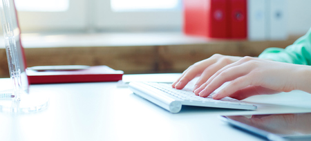 Female office worker typing on the keyboard. Just hands over the table.の写真素材
