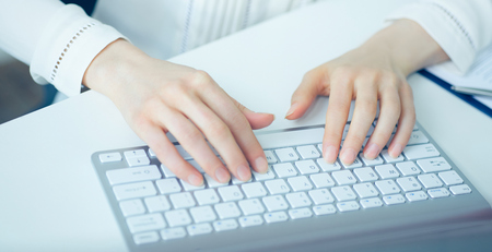 Female hands typing on desktop computer keyboard.の写真素材