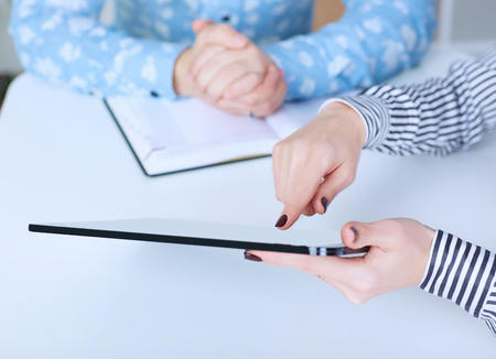 Business woman showing digital tablet to co-worker in office. Just hands over the table.の写真素材