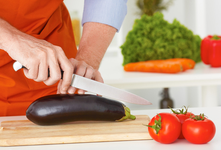Mid section of a man preparing to chop cabbage in the kitchen at home.の写真素材