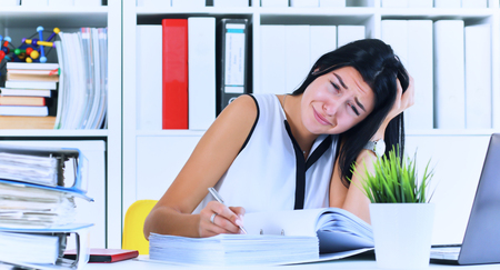 Young female office worker shocked by the huge amount of paper work. Deadline concepts.の写真素材