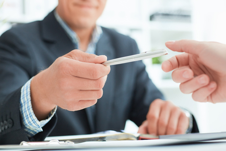 Male arm in suit offer silver pen to sign contract closeup. Strike a bargain for profit, white collar motivation, union decision, corporate sale, insurance agent conceptの写真素材
