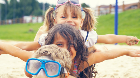 Two girls and a boy lie on the sand on the lake spreading his hands to the sides like the wings of an airplaneの写真素材