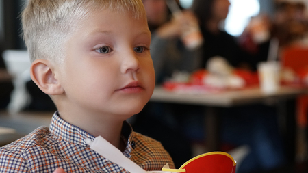 Little Caucasian boy eating ice cream with a plastic spoon into the cafe.の写真素材