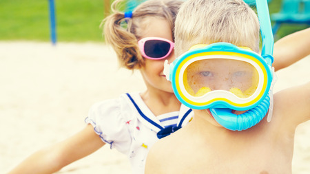 Two happy children, boy and a little toddler girl, brother and sister, playing on a beautiful tropical beach after snorkeling in the ocean having fun during summer vacationの写真素材