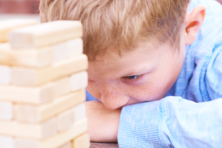 Caucasian kid is playing wood blocks tower game for practicing physical and mental skill.の写真素材