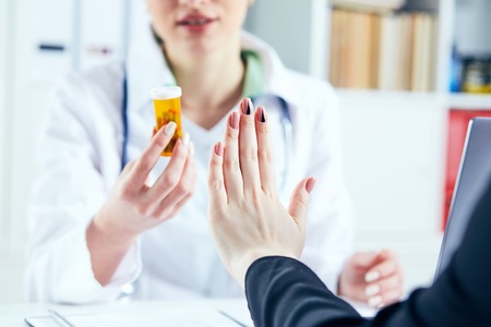 Female patient at the doctor appointment refuses to take prescribed medications, believes that they are useless and these biological drugs will only cause harm to his body.の写真素材