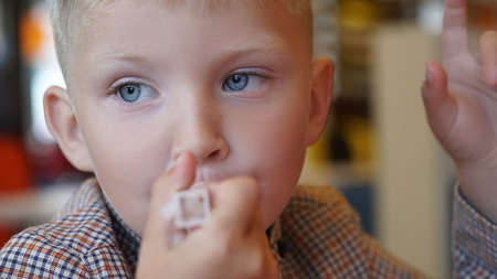 Little Caucasian boy eating ice cream with a plastic spoon into the cafe.の写真素材