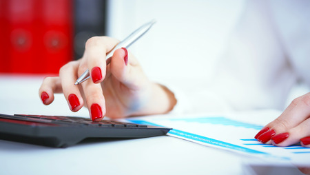 Close up of female accountant or banker hand making calculations. Savings, finances and economy conceptの写真素材