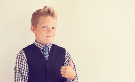 Smiling little schoolboy showing thumb up standing near the white blackboard.の写真素材
