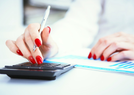 Close up of female accountant or banker hand making calculations. Savings, finances and economy conceptの写真素材
